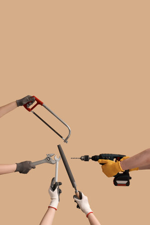 Female and male hands holding different construction tools on beige background
