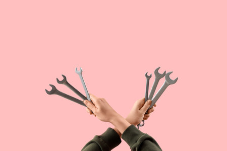 Female hands holding set of wrenches on pink backgroundの写真素材