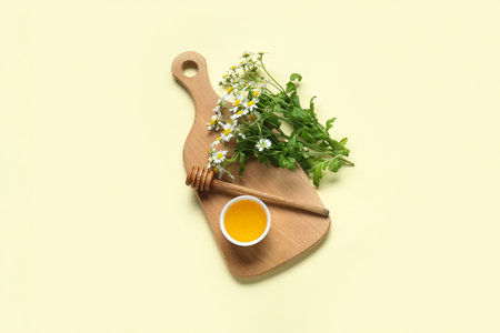 Wooden board with bowl of honey and fresh chamomile flowers on color backgroundの写真素材