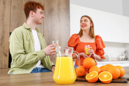 Jug of juice with oranges on table in kitchen, closeupの写真素材
