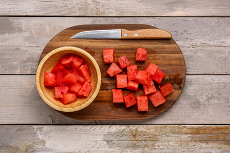 Board and bowl with pieces of fresh watermelon on gray wooden backgroundの写真素材