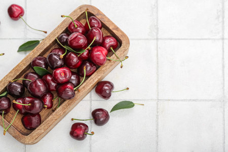 Board with sweet cherry on white tile backgroundの写真素材