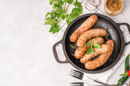 Frying pan of tasty homemade sausages on light backgroundの写真素材