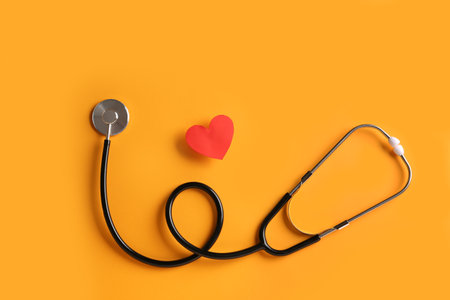 Stethoscope and red heart on yellow background. cardiology conceptの写真素材