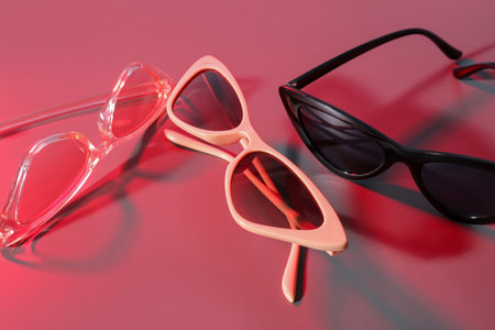 Different stylish sunglasses on red background
