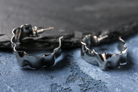 Board with beautiful earrings on blue backgroundの写真素材