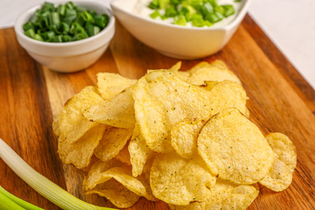 Bowls of tasty sour cream with sliced green onion and potato chips on white backgroundの写真素材