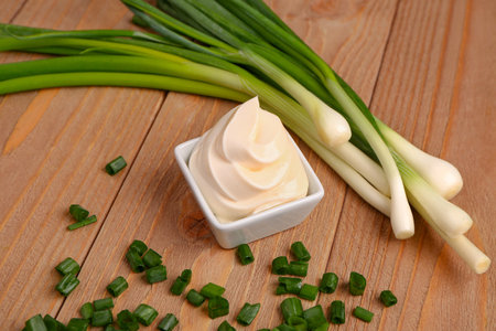 Bowl of tasty sour cream and sliced green onion on wooden backgroundの写真素材