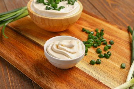 Bowls of tasty sour cream with sliced green onion on wooden backgroundの写真素材