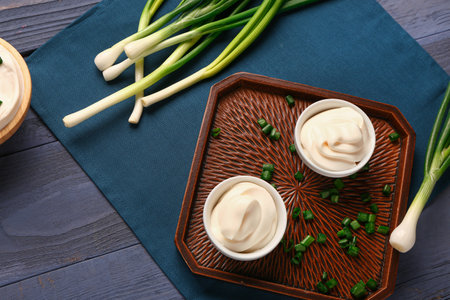 Bowls of tasty sour cream and sliced green onion on blue wooden backgroundの写真素材