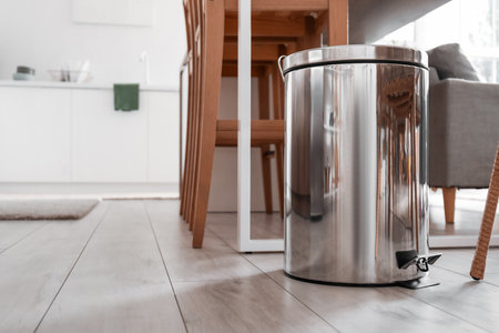 Metallic trash bin near table in interior of modern kitchenの写真素材