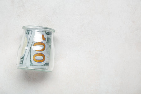 Roll of one hundred dollars banknotes in jar on gray grunge backgroundの写真素材