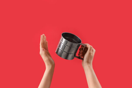 Female hands holding measuring cup on red backgroundの写真素材