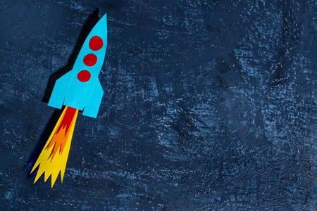 Blue paper rocket on dark grunge backgroundの写真素材