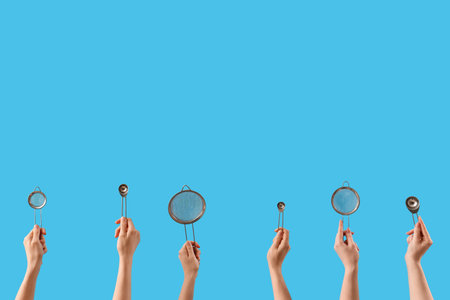 Female hands holding sieves and tea infusers on blue background