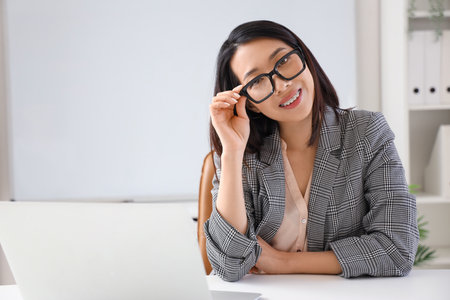 Beautiful Asian businesswoman in stylish eyeglasses in officeの写真素材