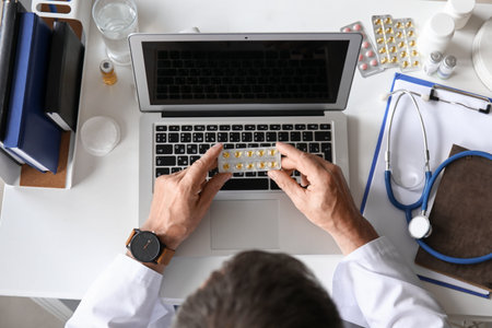 Mature male doctor with pills at desk in clinic, top viewの写真素材