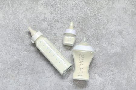 Bottles of milk for baby on gray grunge background