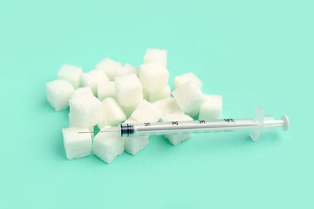 Sugar cubes with syringe for insulin injection on green backgroundの写真素材