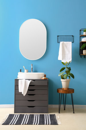 Interior of bathroom with sink on dressing table, mirror and houseplantの写真素材