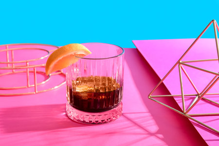 Glass of rum with grapefruit slice and decorative figures on colorful backgroundの写真素材