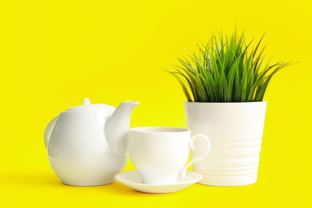 Artificial grass with cup of tea and teapot on yellow backgroundの写真素材