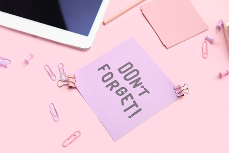 Don't forget reminder with stationery and tablet computer on pink background, closeupの写真素材