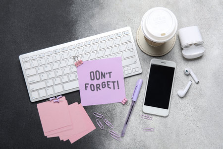 Don't forget reminder with stationery, devices and cup of coffee on black backgroundの写真素材
