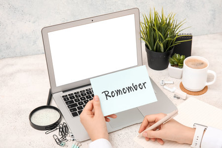 Woman with reminder writing in notebook on grunge table, closeup