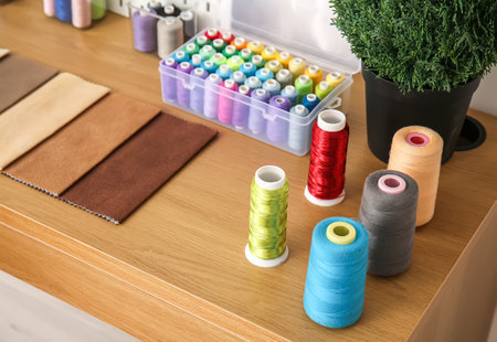 Thread spools with fabric samples on table in atelier, closeup