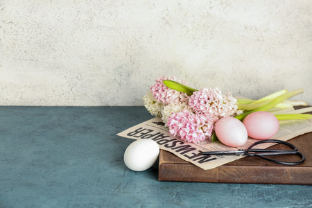 Beautiful hyacinth flowers, Easter eggs and scissors on table near beige wall