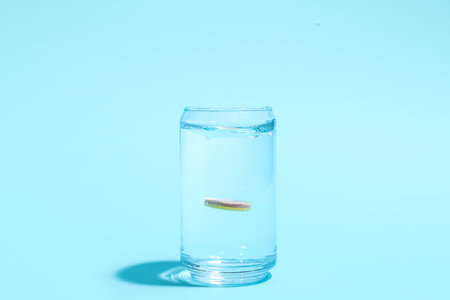 Glass of water with soluble tablet on blue background