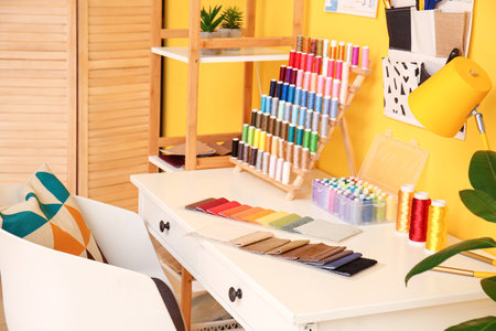 Tailor's workplace with fabric samples and thread spools in stylish atelierの写真素材