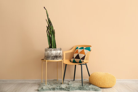 Modern armchair and big cactus in pot near beige tableの写真素材