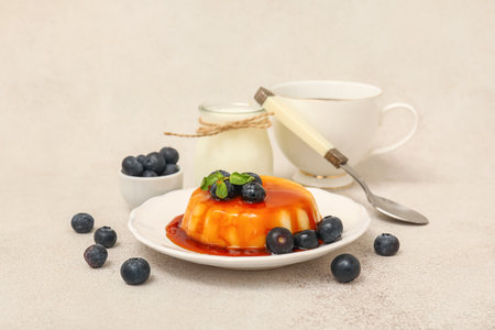 Plate with delicious pudding and blueberries covered by caramel syrup on white grunge backgroundの写真素材