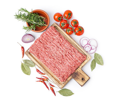Board with fresh minced meat, tomatoes, chili peppers and rosemary isolated on white background