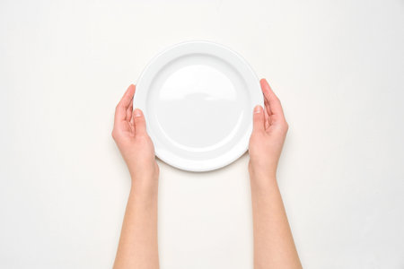 Female hands with empty plate on white backgroundの写真素材