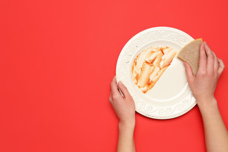 Woman washing dirty plate on red backgroundの写真素材