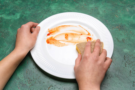 Woman washing dirty plate on green grunge backgroundの写真素材