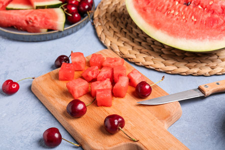 Board with pieces of fresh watermelon and cherries on blue backgroundの写真素材