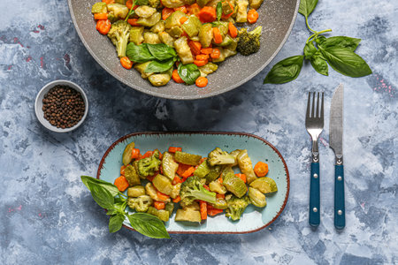 Frying pan and plate with different vegetables on blue backgroundの写真素材