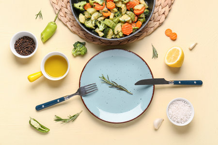 Plate and frying pan with tasty vegetables on yellow backgroundの写真素材