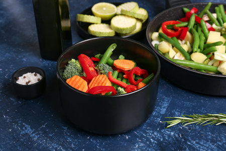 Bowl with fresh vegetables on blue background