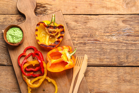Board with tasty grilled bell peppers on wooden backgroundの写真素材