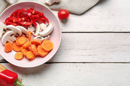 Bowl with fresh vegetables on light wooden backgroundの写真素材
