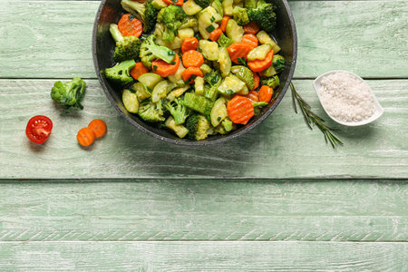 Frying pan with tasty vegetables on green wooden backgroundの写真素材