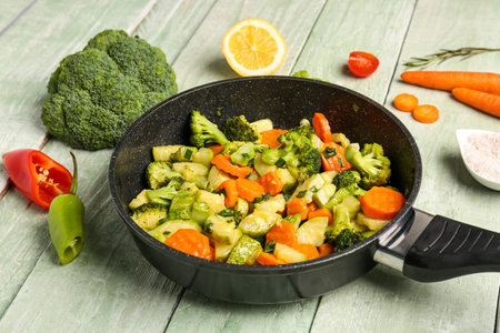 Frying pan with tasty vegetables on green wooden backgroundの写真素材