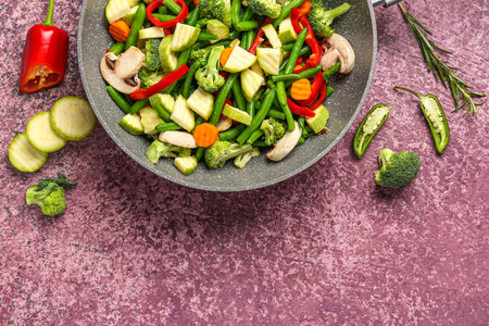 Frying pan with fresh vegetables on purple backgroundの写真素材
