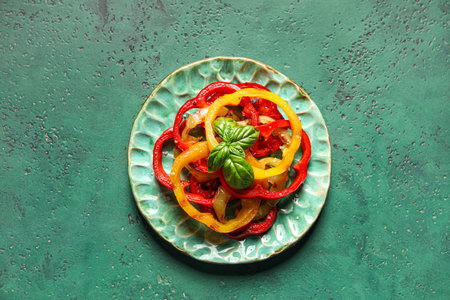 Plate with slices of tasty grilled bell pepper on green backgroundの写真素材