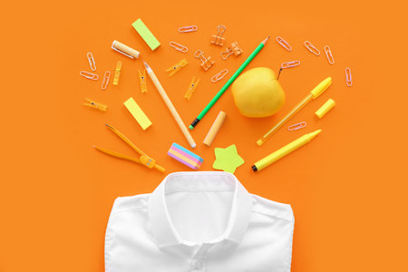 School shirt with fresh apple and different stationery on orange backgroundの写真素材